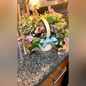 Beautiful floral bouquet arranged in vintage pink metal basket with a light blue